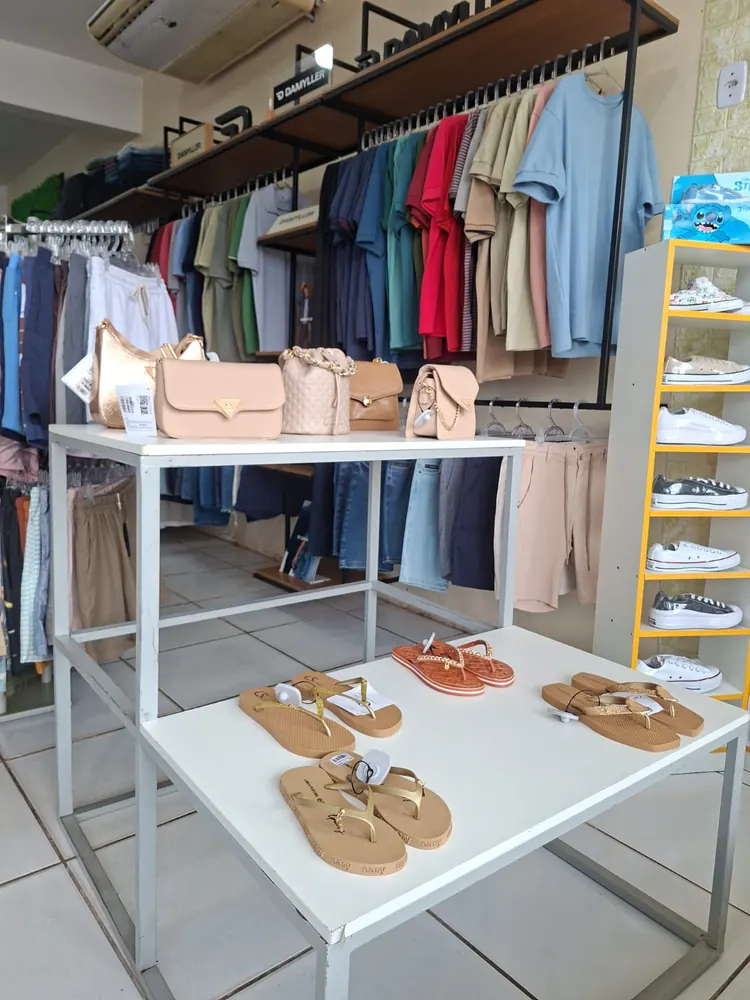 Chinelos e bolsas expostos em mesa, protegidos por etiquetas antifurto