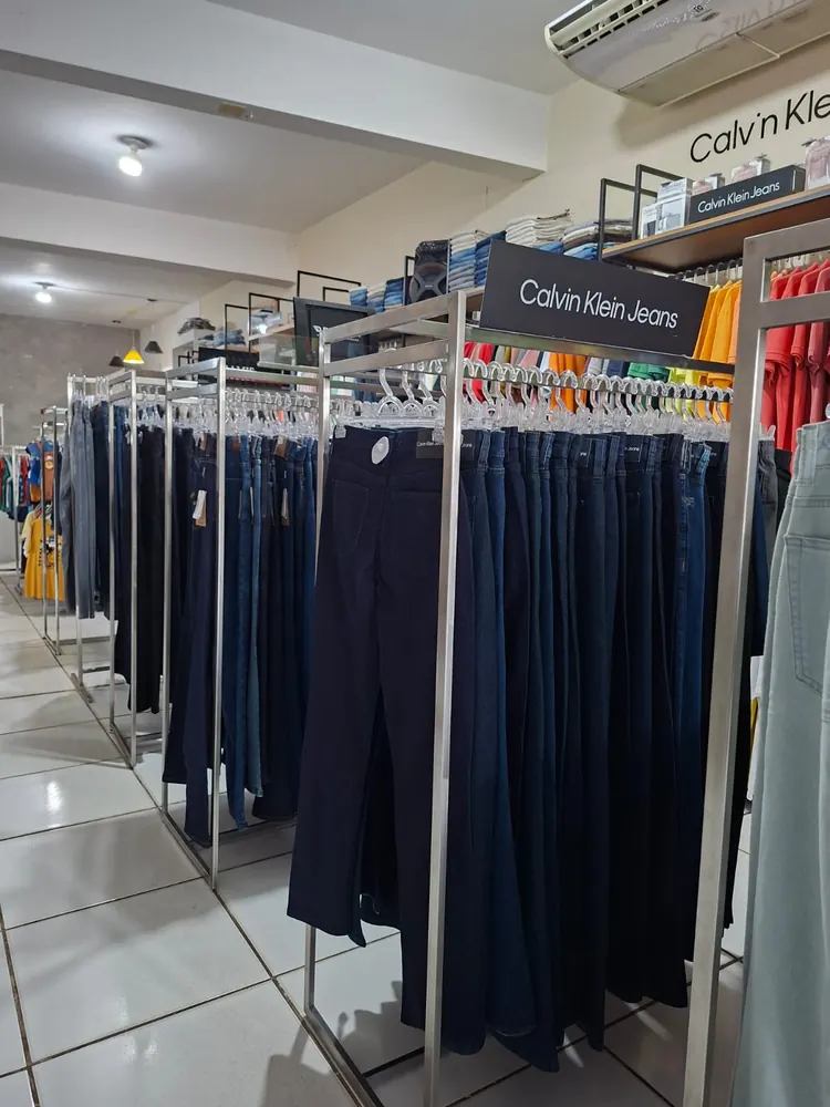 Araras de calças jeans soltas para o cliente tocar e provar, protegidas por etiquetas