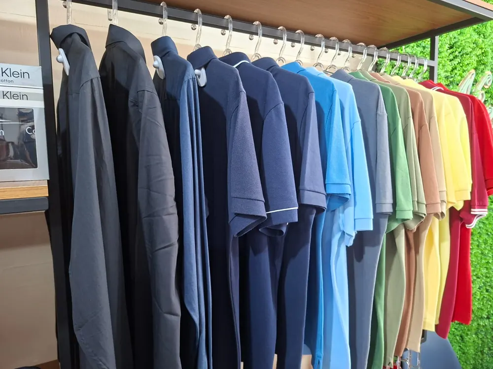Camisas polo expostas na arara, cada peça com etiqueta antifurto rígida