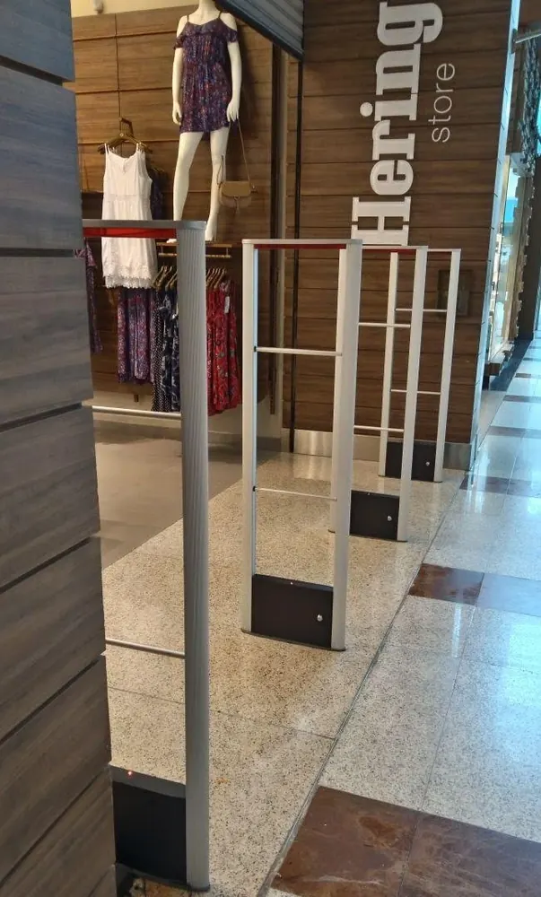 Entrada de loja de moda em shopping com três antenas antifurto de alumínio